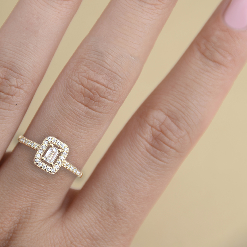 Pierścionek-zaręczynowy-z-żółtego-złota-z-diamentami-centralny-diament-o-szlifie-szmaragdowym-Diamentowa-Esencja-na-dłoni