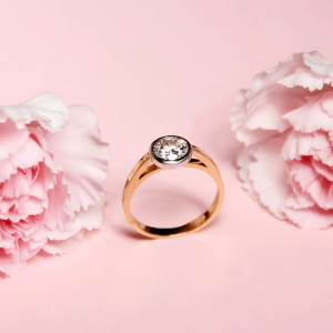 piękny złoty pierścionek z brylantem na różowym tle